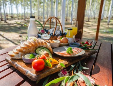 Image 10: A photo of all of the food items contained in the complimentary breakfast. There is bread, milk, orange juice, eggs, tomatoes, avocadoes, bacon, butter and fruit.