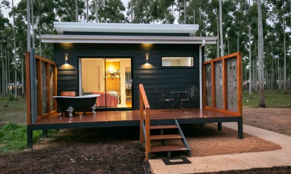 An image showing the back deck of the chalet. There is a clawfoot bath on the back deck and an outdoor setting. The rosegum trees are in the background.